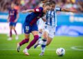 Barcelona Femení player contests the ball with a Real Sociedad opponent.